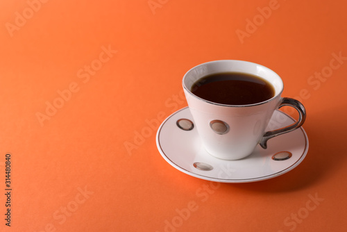  cup of aromatic coffee on an orange trendy background with space for text