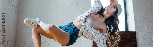 panoramic shot of flexible girl touching cap and dancing hip-hop