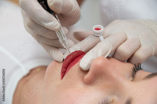 Zbliżenie na pigmentacje ust. Kosmetyczka wykonuje makijaż permanentny ust. Usta po makijażu permanentnym w salonie urody. Zabieg w salonie medycyny estetycznej. 