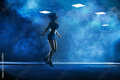 Athletic woman using skipping rope.