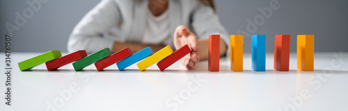 Businessperson Hand Stopping Colorful Blocks From Falling