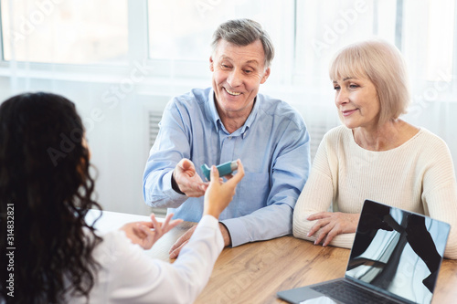 Female physician giving asthma inhaler to elderly couple