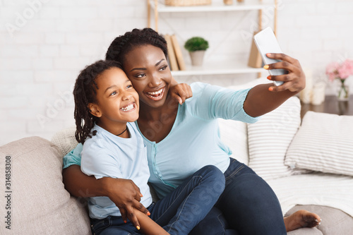 Happy black mom and daughter taking selfie