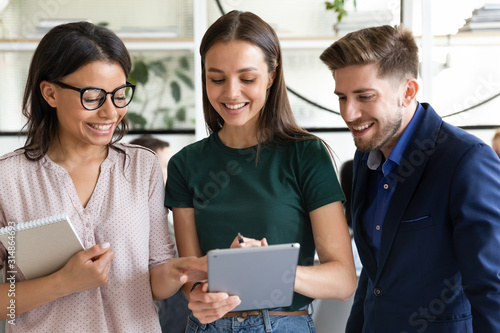 Three diverse colleagues discuss common task or project using tablet