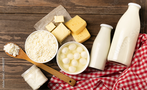 Dairy sour milk products on a wooden dark rustic background. Milk, kefir, yogurt, butter, cheese assortment. Flat layout