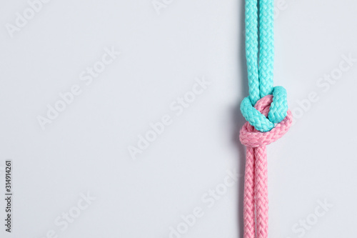 Colorful ropes tied together with knot isolated on white, top view. Unity concept