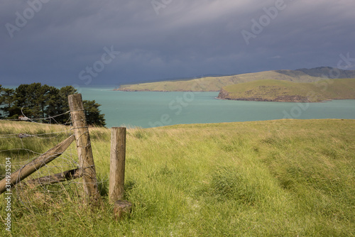 The entrance to Lyttelton Harbour, Whakaraupo, from Godley Head just after a major storm passed through, with the dark clouds still visible in the distance. Canterbury, New Zealand.
