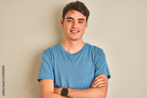 Teenager boy wearing casual t-shirt standing over isolated background happy face smiling with crossed arms looking at the camera. Positive person.