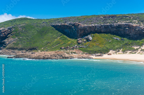 Picturesque seaside landscape with sandy beach and green grassy hills