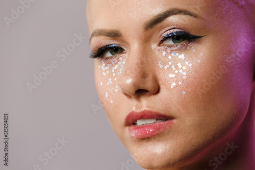 Portrait of gorgeous young half-naked bald woman with glitter face
