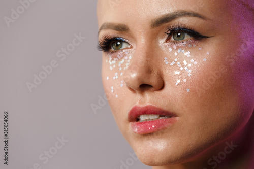 Portrait of gorgeous young half-naked bald woman with glitter face