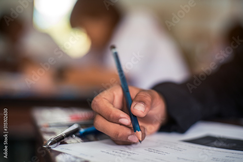 Hand of Student doing test or exam in classroom of school with stress