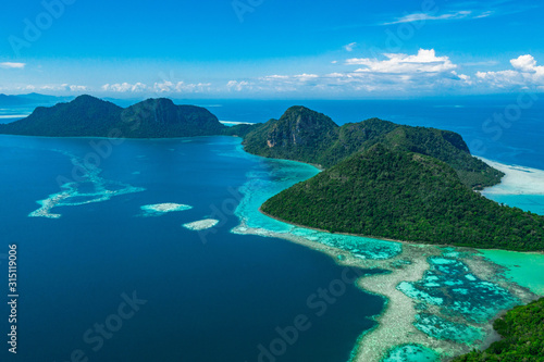 Amazing tropical paradise islands from air with blue turquoise blue lagoon water and coral reef. Aerial view of Bohey Dulang island panorama. Hawaii, Philippines, French polynesia.