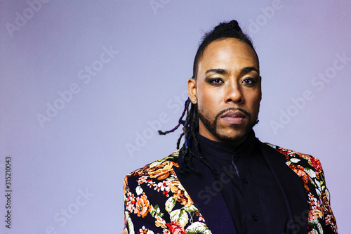 Studio portrait of a man wearing a flower patterned suit and dreadlocks