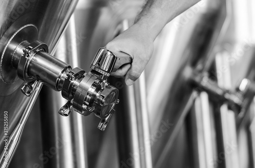 brewer operating industrial beer brewing equipment in brewery interior