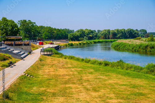 Promenade along the Warta river bank with a city park in the historic quarter of Konin, Poland