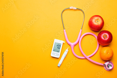 Digital glucometer, lancet pen, stethoscope and fruits on color background. Diabetes concept