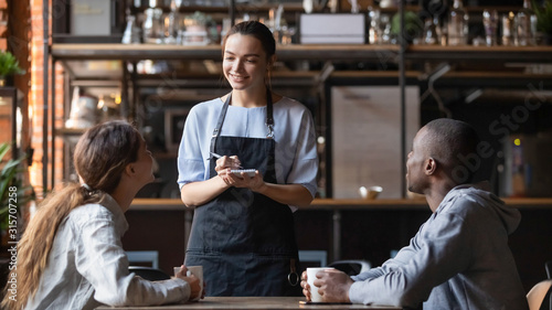 Smiling waitress taking order from multiracial clients