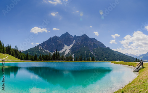 Mountains peaks and snow reflected in green lake