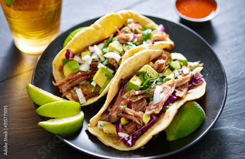 pork carnita tacos close up with lime wedges and red cabbage