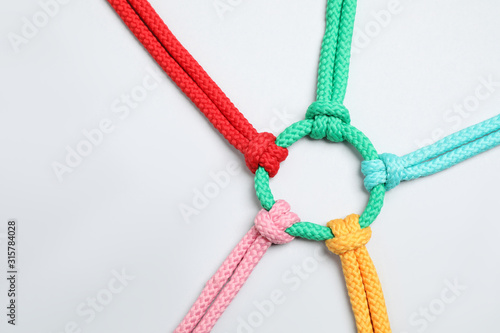 Colorful ropes tied together on white background, top view. Unity concept