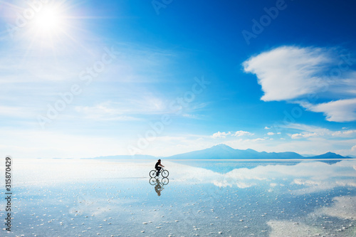 Woman riding a bicycle on the Salar de Uyuni salt flat in Bolivia. South America landscapes