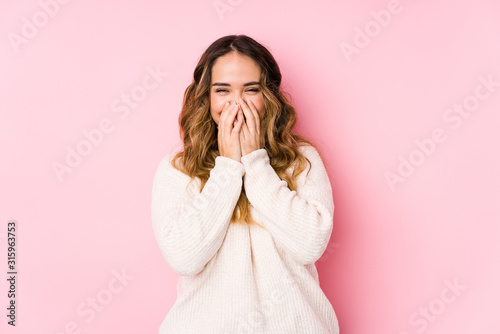 Young curvy woman posing in a pink background isolated laughing about something, covering mouth with hands.