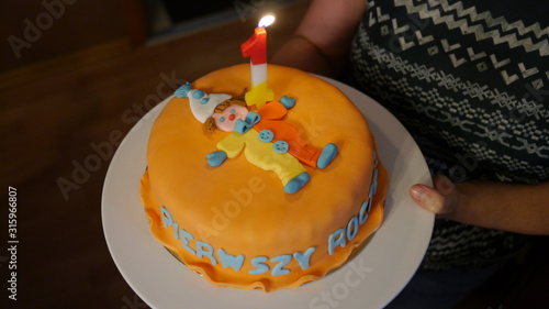 Tort urodzinowy z napisem w języku polskim pierwsze urodziny i świeczką jeden roczek