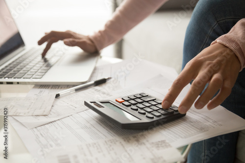 Close up cropped image young woman calculating monthly expenses.