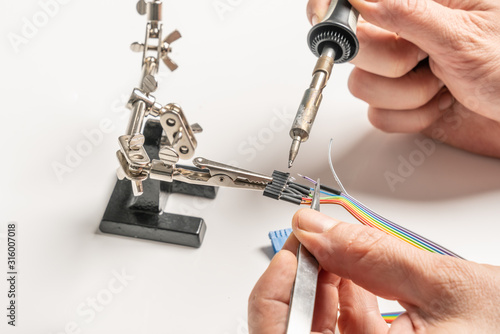 technician solders cable to a plug with a soldering iron