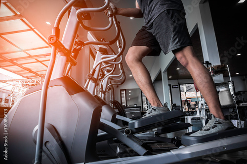 Young man working out on an elliptical trainer in gym