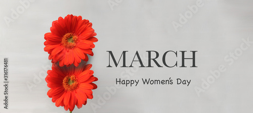 Two red Gerbera flowers and "March. Happy Women's day" text in English