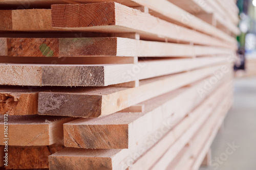 Warehouse or factory for sawing boards on sawmill indoors. Wood timber stack of wooden blanks construction material. Logging Industry.