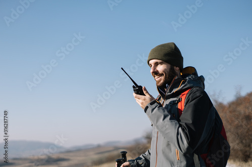 Smiling man speaking on two-way radio for hiking