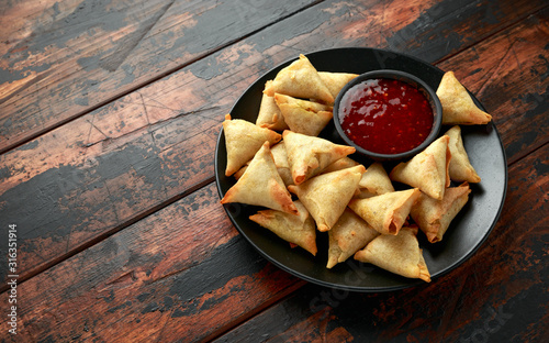 Fresh Indian Samosa with dipping sweet chili sauce on wooden table