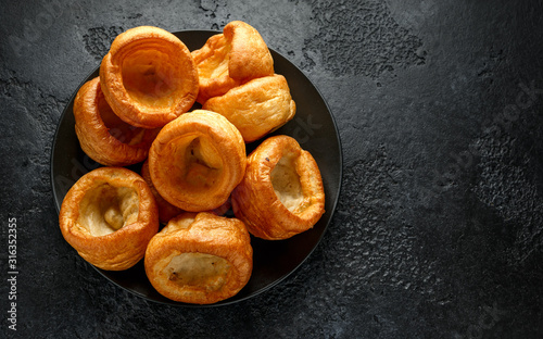 Traditional English Yorkshire pudding side dish on black plate and background