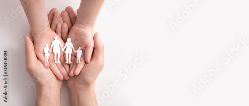 Family care concept. Hands with paper silhouette on table.