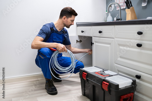 Plumber Cleaning Clogged Sink Pipe