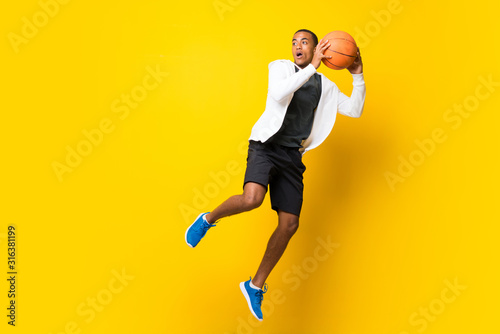 Afro American basketball player man over isolated yellow background