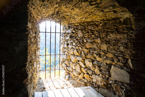 Vergittertes Fenster eingemauert in einer alten Naturstein Mauer