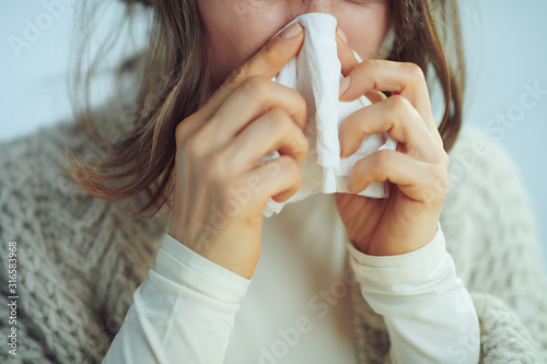 Closeup on ill elegant woman wiping nose with napkin