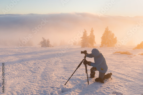 Photographer in winter time. Mountains during snowy weather. Holidais in Alps