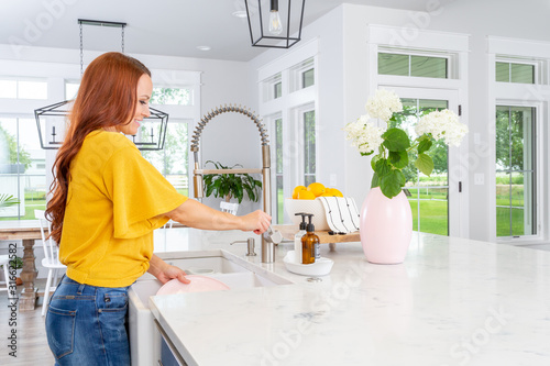 A woman washing dishes in a modern farmhouse kitchen.