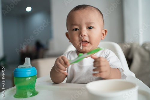 baby boy with snot coming from his nose while sitting on high chair