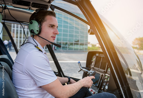 A Airline pilot wearing uniform sitting inside with epaulettes and headset to connect with another pilot on board passenger.