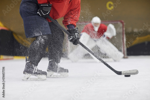Low section action shot of unrecognizable hockey player shooting pluck into gate during