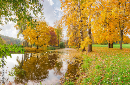 Scenic lake in autumn park with trees on shores