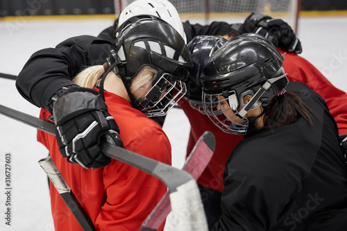 High angle portrait of female hockey team huddling for motivation before sports match