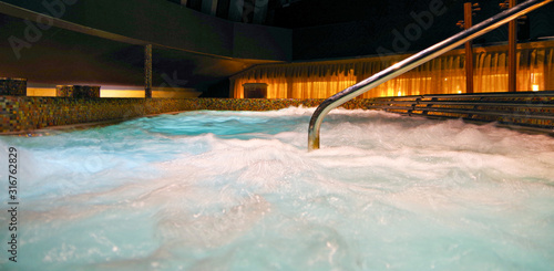 Big whirlpool or thalasso and thalassotherapy pool inside spa and wellness thermal suite on luxury cruise ship liner or cruiseship