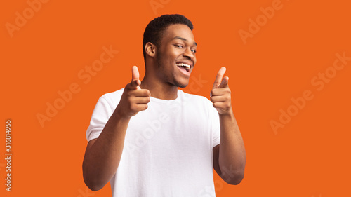 Happy afro guy choosing you over orange background